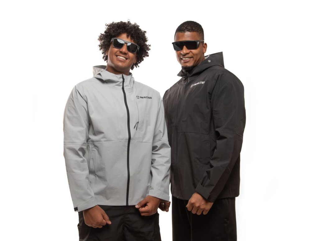 Two men wearing sunglasses and winter jackets, smiling confidently.