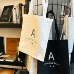 Elegant tote bags on display with books in a chic store setting.