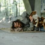 A homeless man sleeping under a bridge, highlighting urban poverty and homelessness.