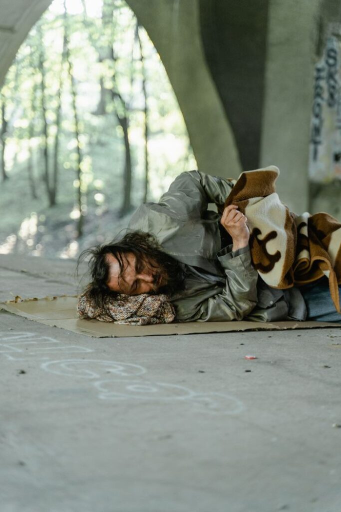A homeless man sleeping under a bridge, highlighting urban poverty and homelessness.